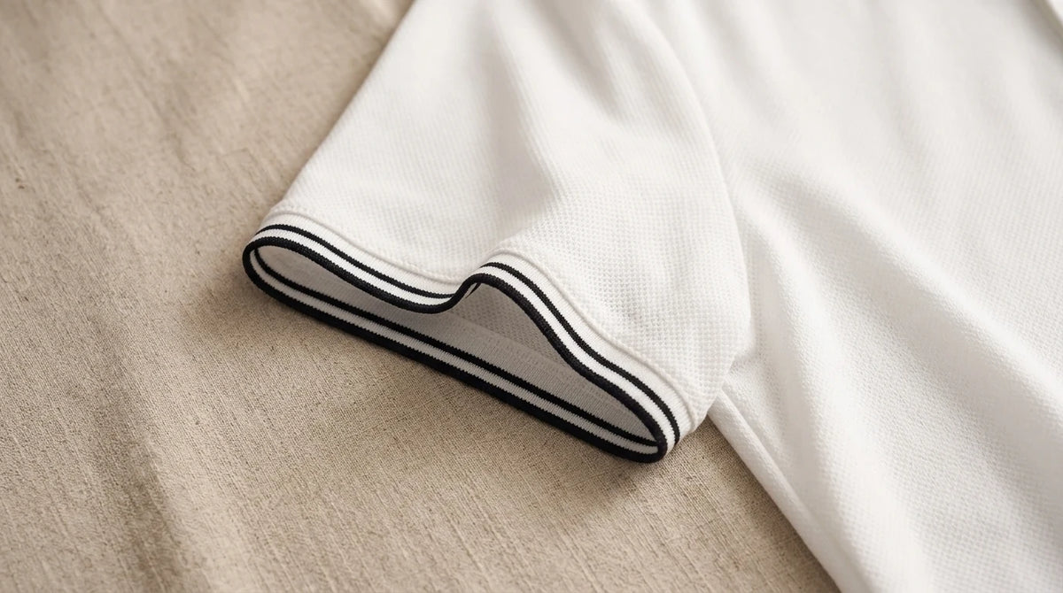 Close-up of the twin black-tipped sleeve hem on white piqué